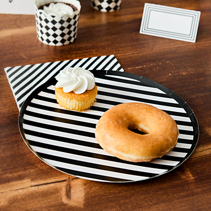 zwart wit gestreept bordje met een donut en een matchende servet liggen op een bruine tafel