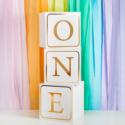 witte blokken met gouden tekst ONE voor een regenboog achtergrond