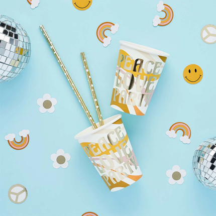Bekers met de tekst peace love party liggen op een blauwe achtergrond naast confetti met smileys, madeliefjes en regenbogen