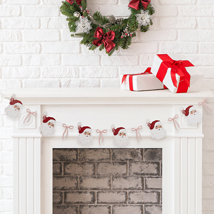 slinger met kerstmannen en roze strikjes hangt aan een witte open haard