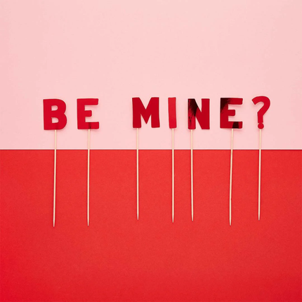 Taart topper met de tekst be mine? op een lichtroze en rode achtergrond