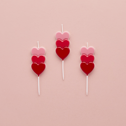 kaarsjes met rode, wijnrode en roze hartjes op een roze achtergrond