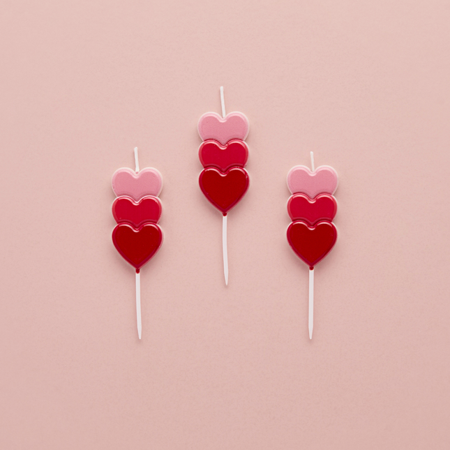 kaarsjes met rode, wijnrode en roze hartjes op een roze achtergrond