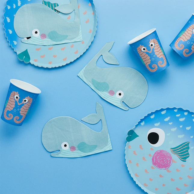 servetten in de vorm van een walvis met een gezichtje liggen op een blauwe tafel naast bordjes in de vorm van een kogelvis en zeepaardjes