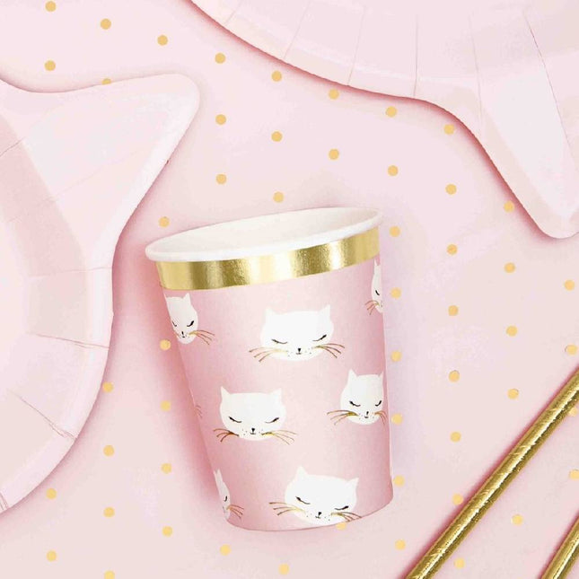 Beker met daarop witte katjes op een tafel met gouden stipjes