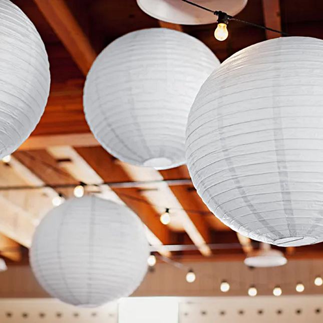 witte lampionnen hangen onder een lampjesslinger aan het plafond