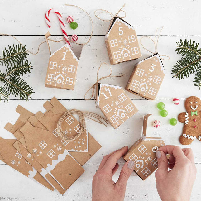 Persoon zet adventkalender van gingebreadhuisjer in elkaar
