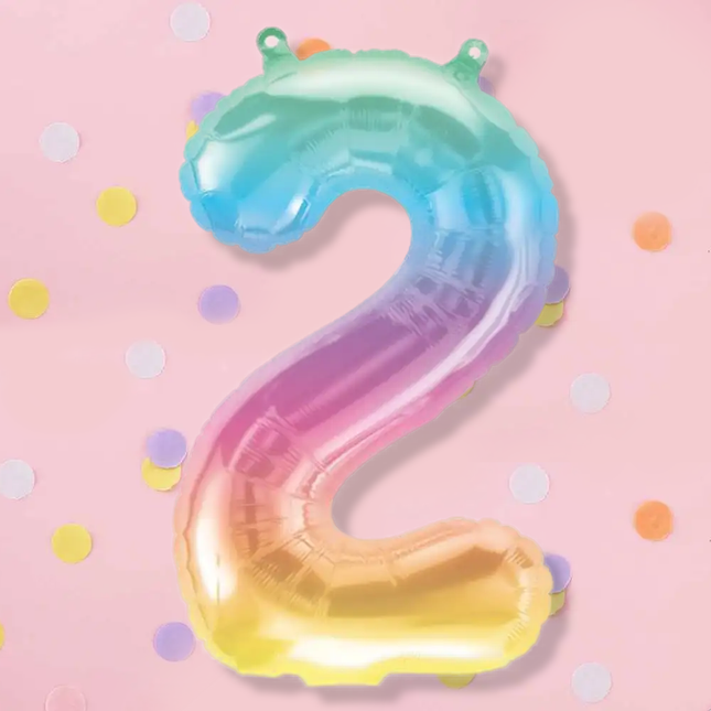 Pastel cijferballon met regenboogkleur op een lichtroze achtergrond met paarse, witte, gele en oranje confetti