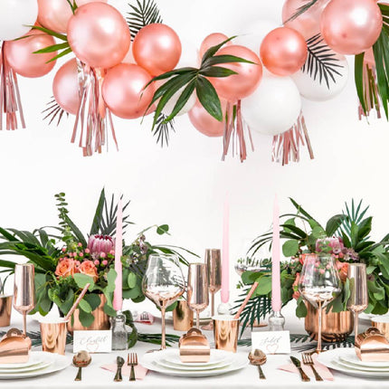 Versierde tafel met planten en rosé gouden tafeldecoratie en ballonnen