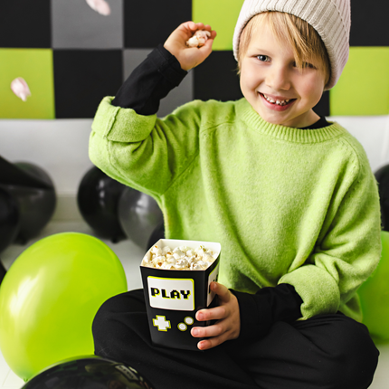 Jongen met een groene trui zit met een popcorn bakje