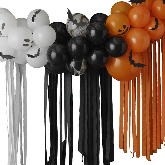Halloween ballonnenboog met papieren vleermuizen erop en crepe slingers eronder