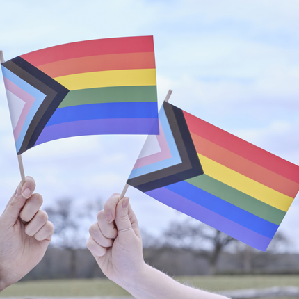Twee handen met vieze nagels houden regenboog vlaggetjes vast
