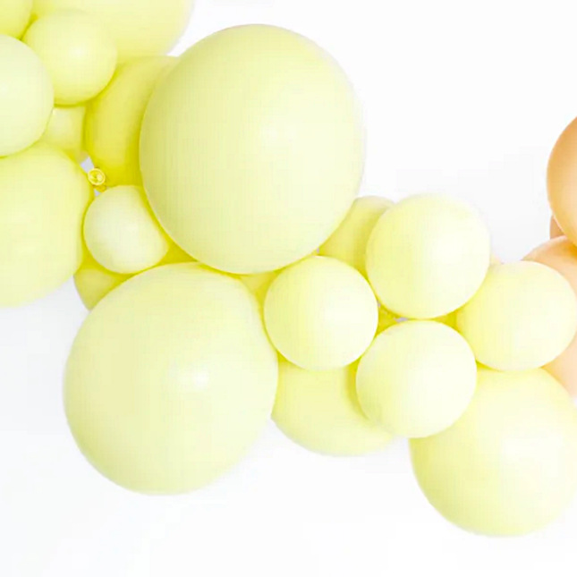 Pastel gele ballonnen in een ballonnenboog met oranje ballonnen