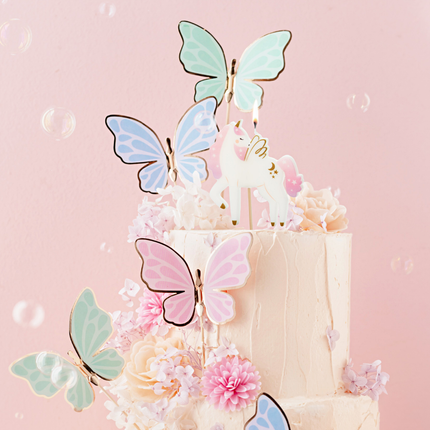 verjaardagstaart versierd met pastel vlinders en een eenhoorn kaars