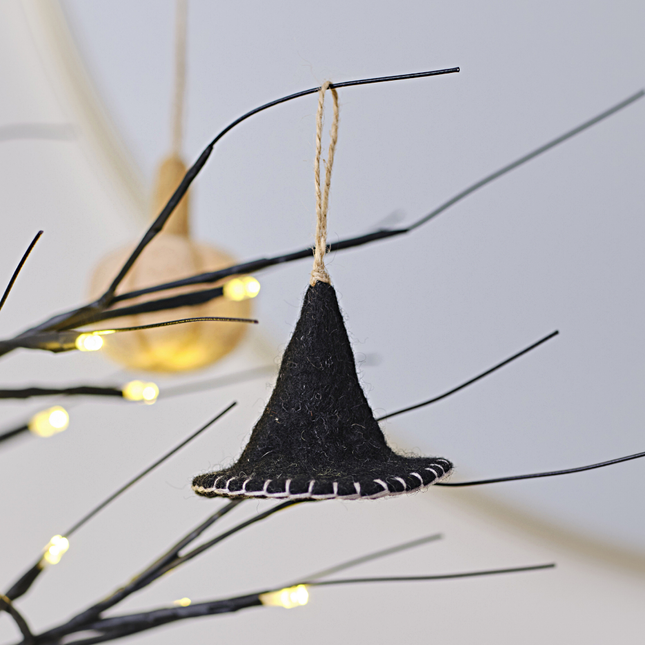Zwarte heksenhoed van vilt hangt aan een lichtgevende, zwarte boom