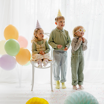 kinderen staan naast een ballonstandaard gevuld met pastel ballonnen