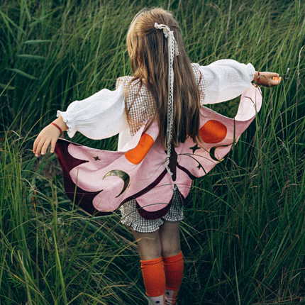 meisje met vlinder vleugels in het roze en paars staat in het gras