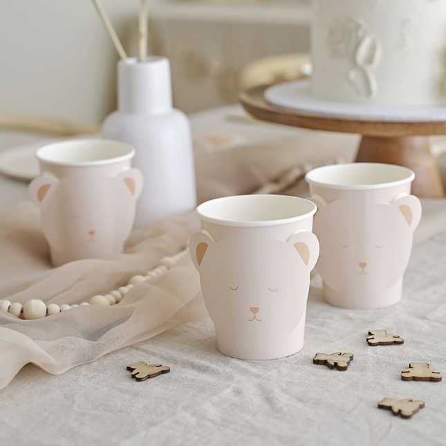 Bekers met een beren gezicht erop staan op een wit kleed met houten confetti