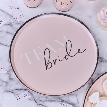 Papieren bordje in het roze met zwarte rand en de tekst team bride staat op een marmeren tafel met roze confetti