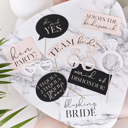 Photo booth props in het roze, zwart en wit liggen op een marmeren tafel