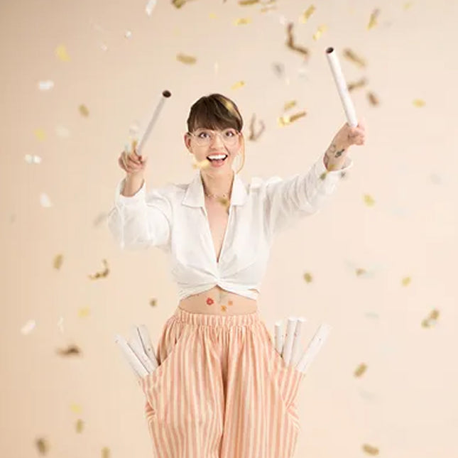 Vrouw gebruikt twee confetti sticks en is omringd door confetti