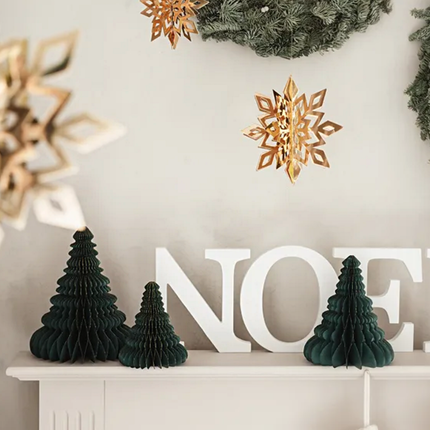 Gouden en donkergroene kerstversiering hangt boven een schouw