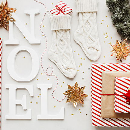 Witte letters noel liggen naast gouden en rode kerstversiering