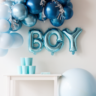 Lichtblauwe follieballonnen met de tekst 'boy' boven een tafel met lichtblauwe bekers en een blauwe ballonnenboog
