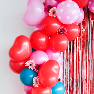 ballonnenboog met een rode backdrop en roze en rode hartvormige ballonnen