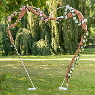 Rose goud drapeerdoek hangt over een witte stanaard en is versierd met roze en witte rozen