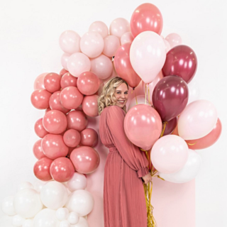 Vrouw in een roze jurk houd pastel roze ballonnen vast