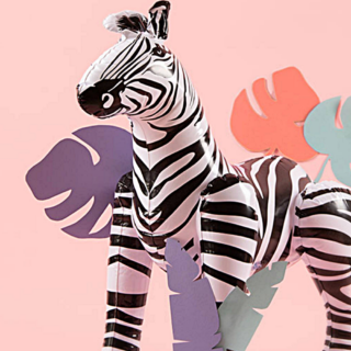 Opblaasbare zebra staat voor een roze achtergrond met palmbladeren