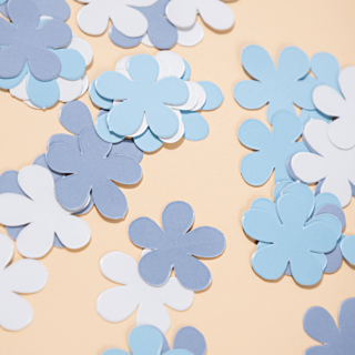 blauwe en witte confetti bloemen liggen op een gele ondergrond