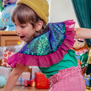 meisje met een gele muts en een kraag met groen en paarse pailletten en violet tule