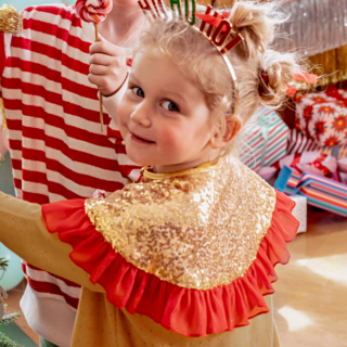 meisje met een gouden pailletten kraag versierd een kerstboom