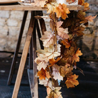 slinger met herfstbladeren hangt aan een houten tafel