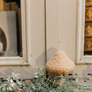 houten paddenstoel met beige teddy stof staat voor een kozijn en is versierd met kunstbloemen